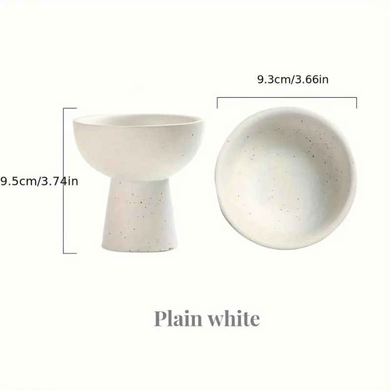 A minimalist white ceramic bowl with a speckled design, featuring a modern pedestal base. The bowl has a smooth, rounded interior and a slightly tapered base.