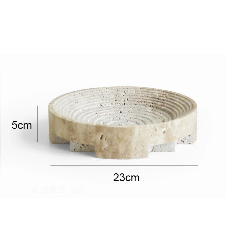 A round, beige dish crafted from travertine stone features textured concentric circles on the inside. Perfect for home styling, it measures 23 cm in diameter and 5 cm in height, adding an organic texture to any space.