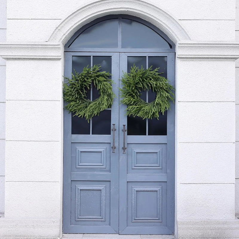 Two green wreaths on a blue double door.