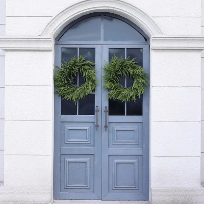 Two green wreaths on a blue double door.