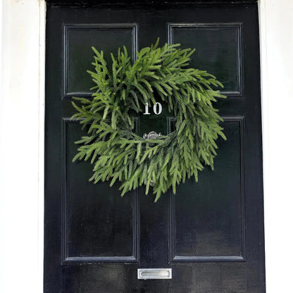 A green wreath on a black door with the number 10.