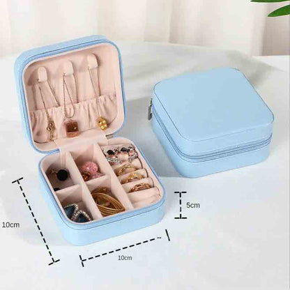 An open light blue square jewelry box filled with various necklaces, earrings, and rings, with a closed matching box in the background, showing dimensions of 10cm x 10cm x 5cm.