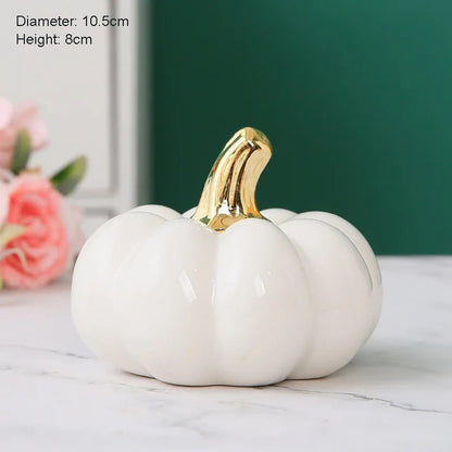 A single small glossy white ceramic pumpkin with a golden stem sits on a marble surface, with text indicating its diameter and height.