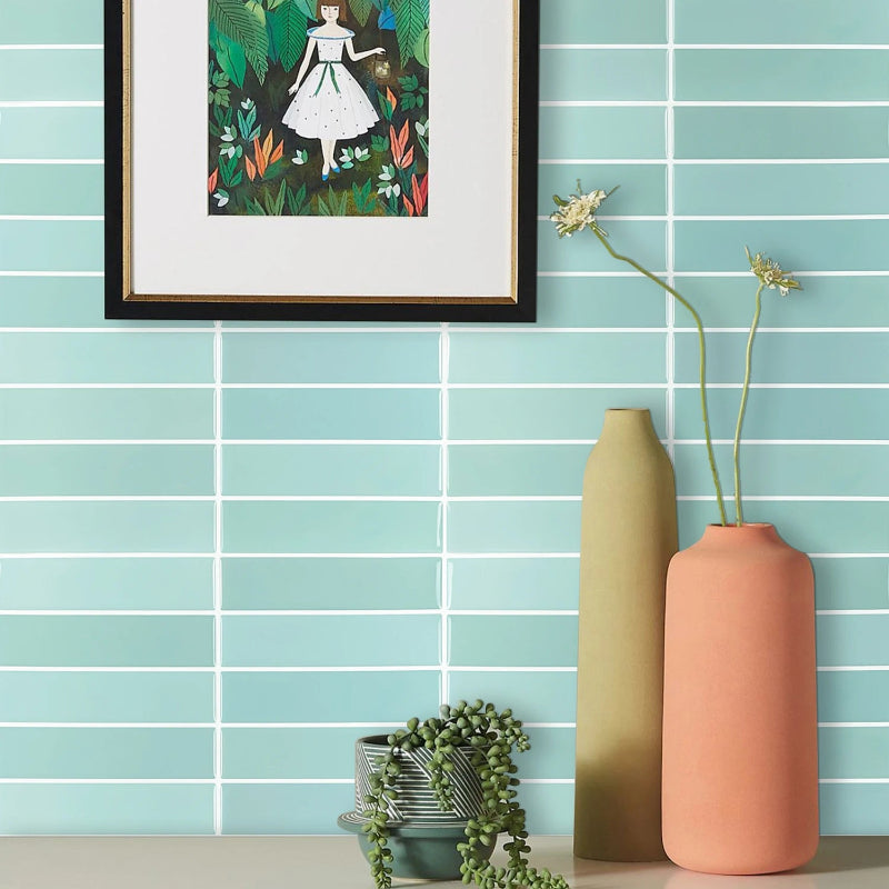 Aquamarine subway tiles with a framed picture and vases.