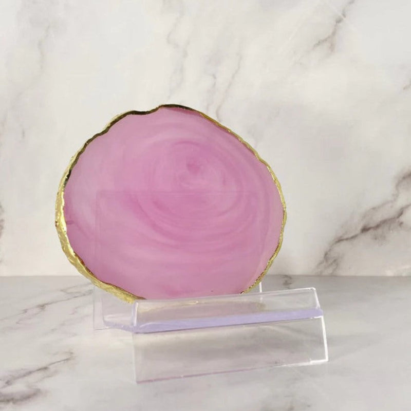 A polished resin agate coaster with vibrant natural hues of pink, showcasing its intricate banding and glossy finish.