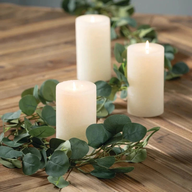 Eucalyptus garland styled as a centerpiece on a dining table, intertwined with pillar candles and fairy lights, creating a serene, natural ambiance.