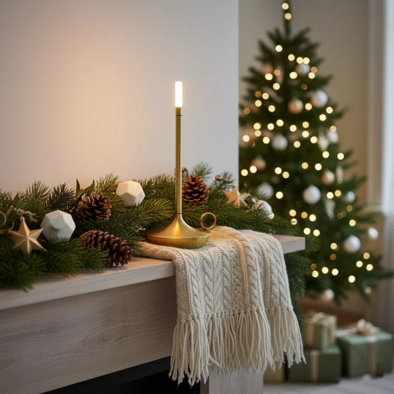 Decorative Christmas mantel with candles, garland, and a lit Christmas tree in the background.