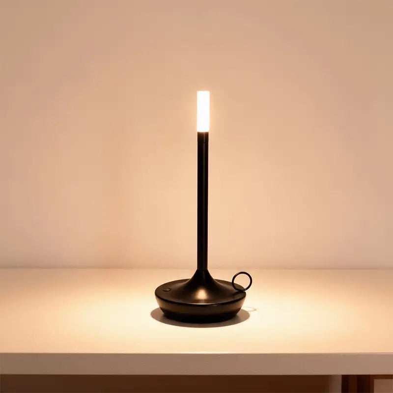 A slender black LED desk lamp is on, casting a warm light.