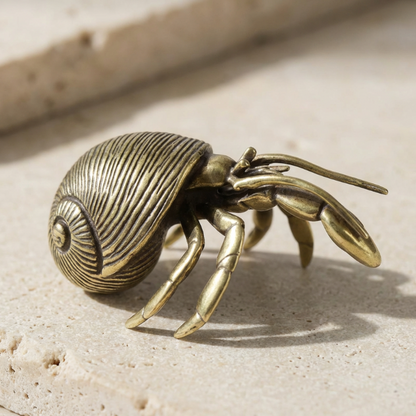 Bronze hermit crab figurine on a sandy surface