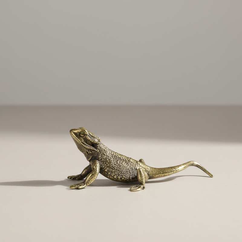 Bronze lizard figurine on a beige surface with a neutral background
