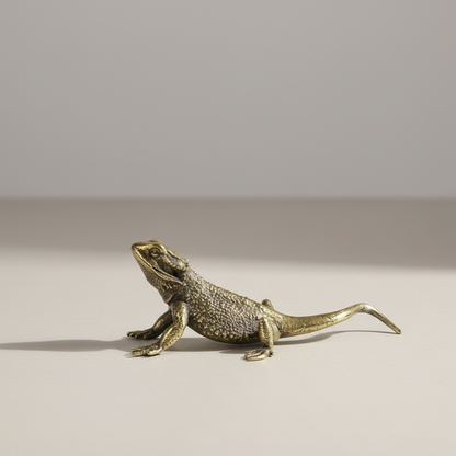 Bronze lizard figurine on a beige surface with a neutral background