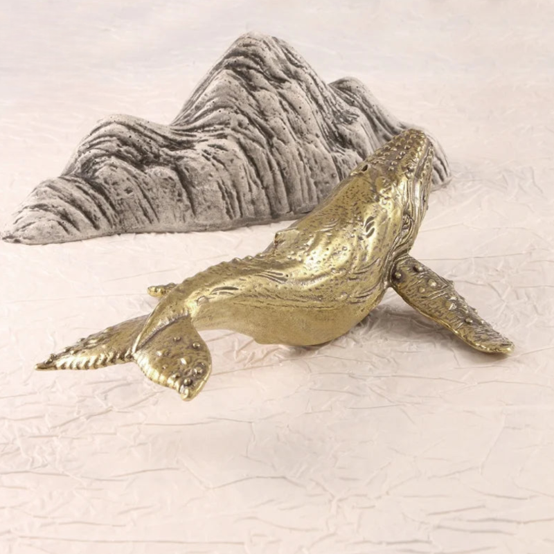 Gold whale figurine on a textured white surface