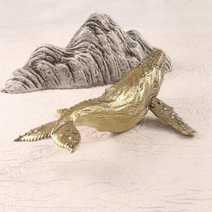 Gold whale figurine on a textured white surface