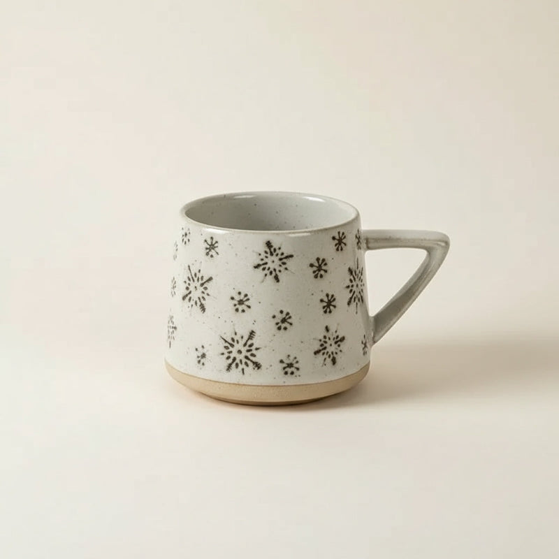 Ceramic mug with black floral patterns on a beige background
