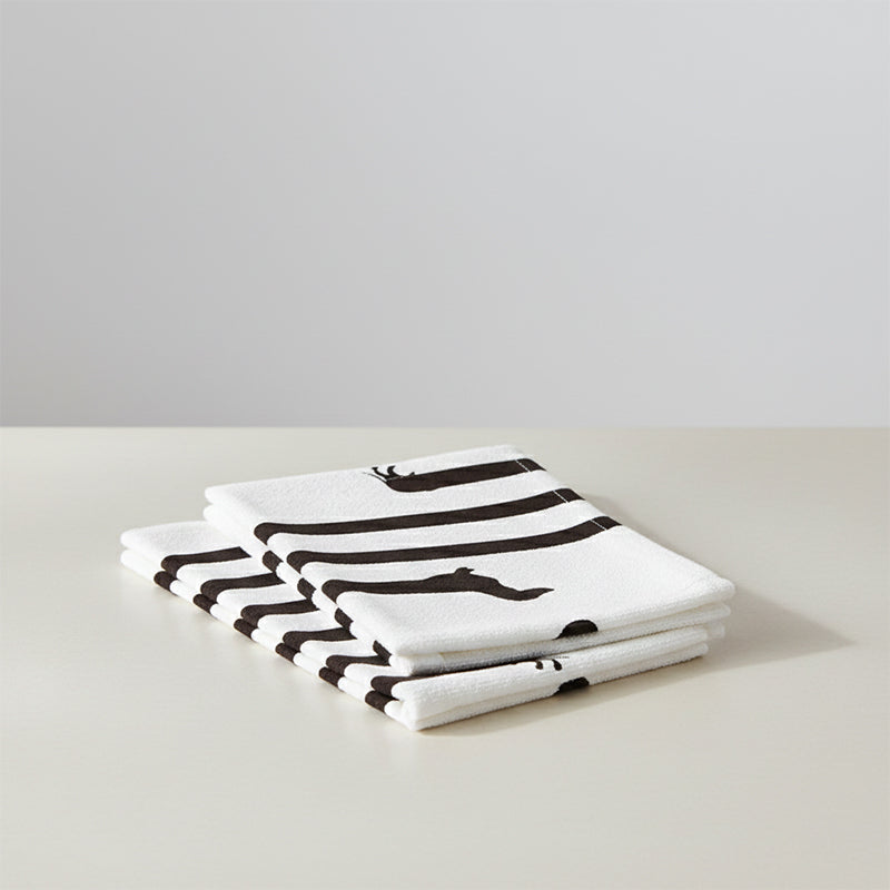 Folded white towel with thick black stripes and a subtle dachshund pattern.