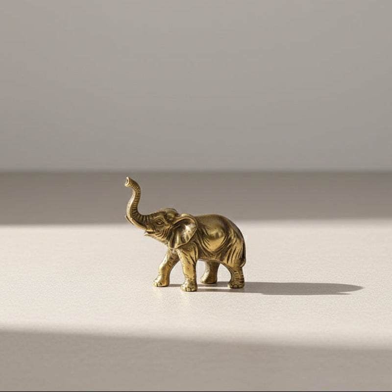 Small brass elephant figurine with its trunk raised.