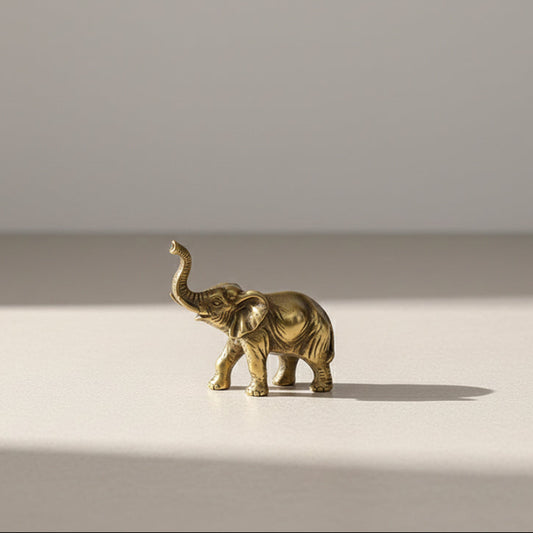 Small brass elephant figurine with its trunk raised.