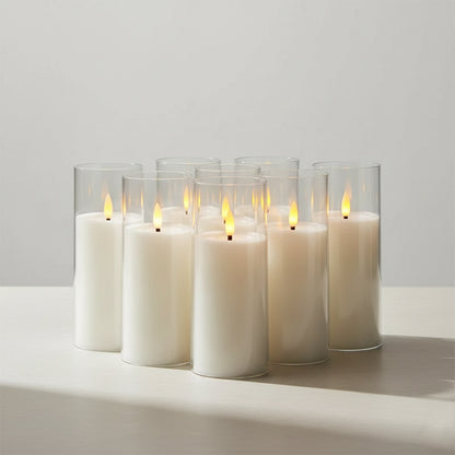 Set of six white candles in glass holders on a light surface with a neutral background