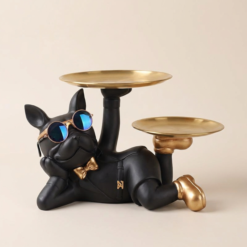 Black dog figurine with gold shoes and sunglasses holding two gold plates on a beige background