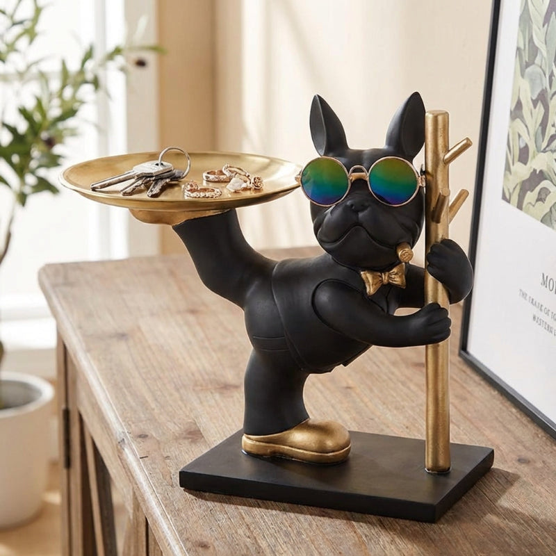 Black dog figurine with sunglasses holding a gold tray on a wooden surface