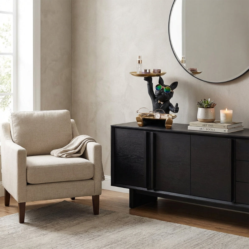 Living room with beige armchair, black sideboard, and decorative items.