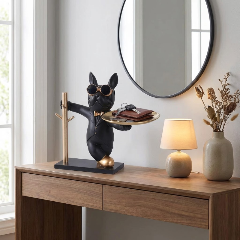 Decorative statue of a dog holding a tray with a wallet on a wooden table.