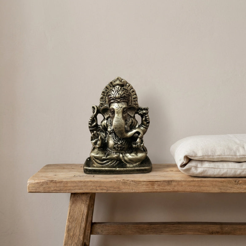 Bronze statue of a deity on a wooden table with a beige background