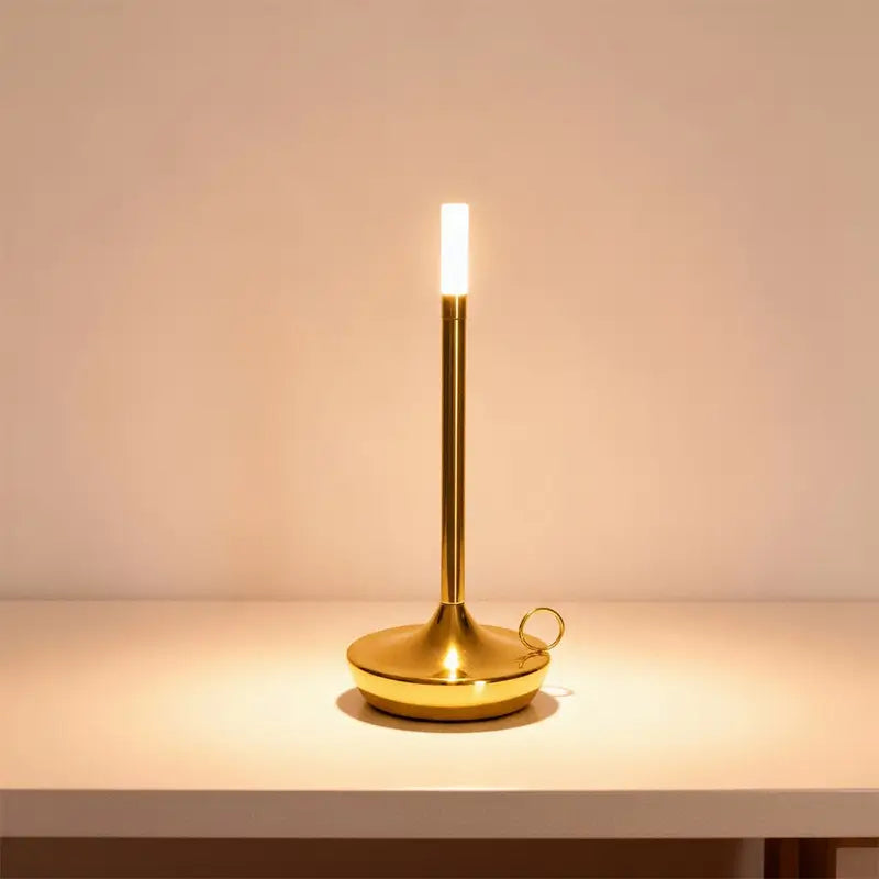 A slender gold LED desk lamp is on, casting a warm light.