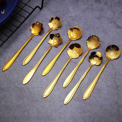 Eight golden flower spoons on a gray surface.