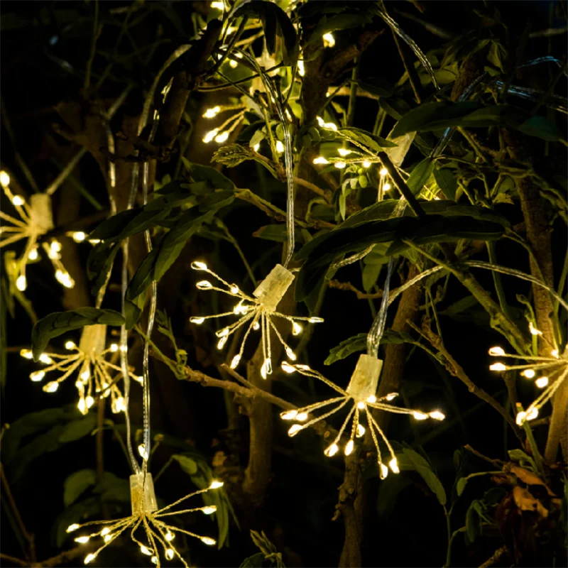 Lit dandelion-shaped string lights hanging in dark foliage.