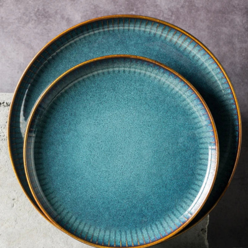 Two round blue dinner plates with golden rims.
