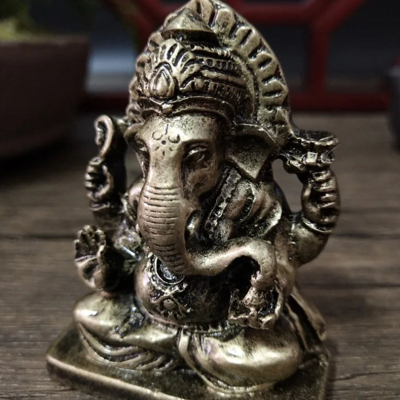 Bronze statue of a deity with elephant head and traditional attire on a wooden surface