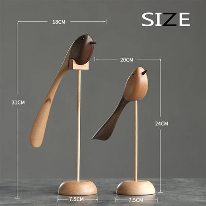 Product image of two decorative wooden bird figurines on stands, showing their dimensions: the taller bird is 31cm high by 18cm long, and the shorter is 24cm high by 20cm long, both with 7.5cm bases.