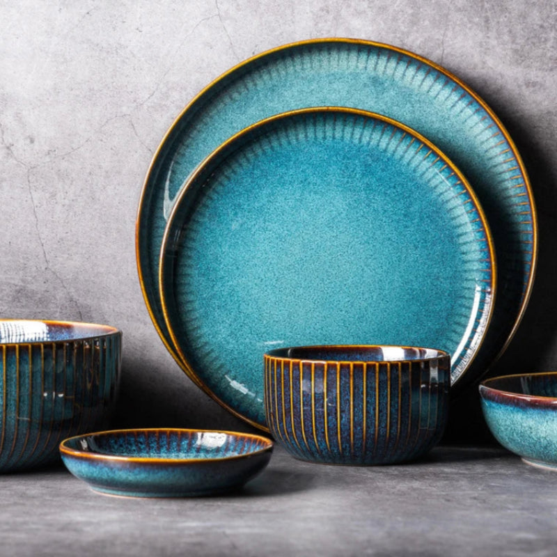 A collection of blue ceramic dishes, including plates and bowls, with golden rims.