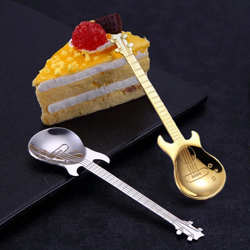 Guitar-shaped spoons next to a slice of cake on a dark surface