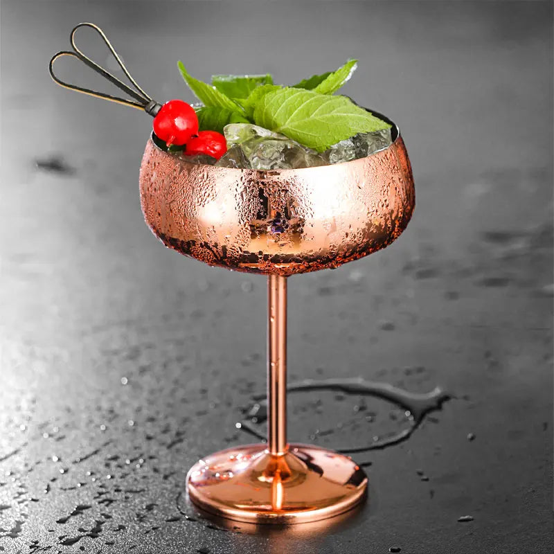 A chilled copper cocktail glass with ice, mint, and berries.