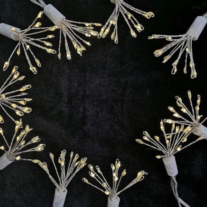 Dandelion-shaped string lights arranged in a circle on a dark surface.