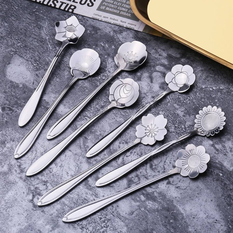 Eight silver flower spoons on a gray surface.