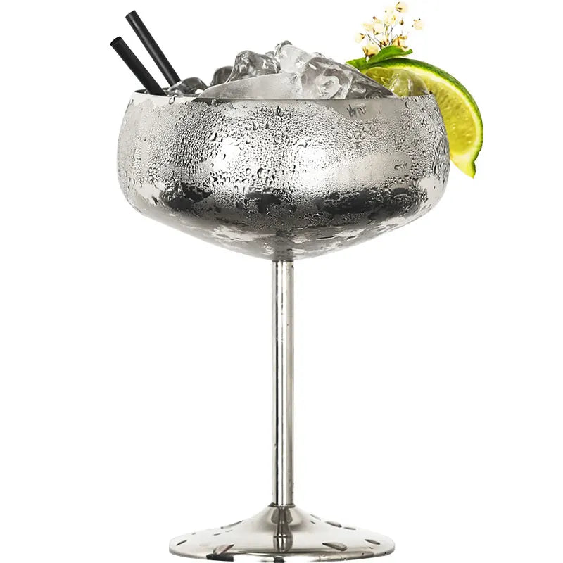 A frosted silver metal cocktail glass with ice, a lime slice, and two straws.