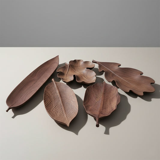 Collection of five wooden bowls or serving dishes shaped like different types of leaves.