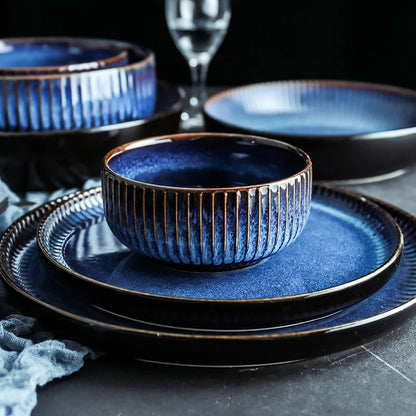 A full place setting of dark blue ceramic dinnerware with a fluted texture, including a plate and a bowl.