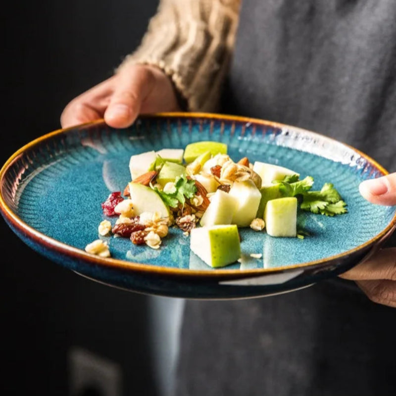 A person holding a blue plate with a fresh salad.