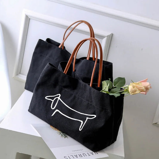 Two black canvas tote bags, one with a white dog outline.