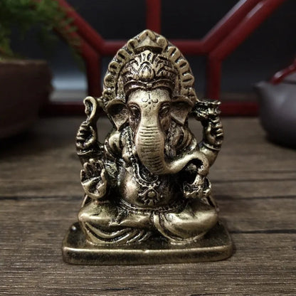 Bronze statue of a deity with elephant head on a wooden surface