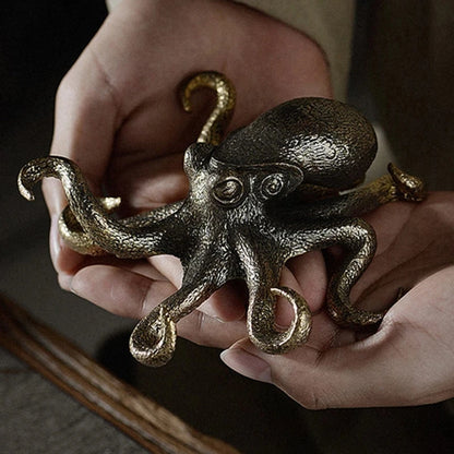 Bronze octopus figurine held in hands against a neutral background