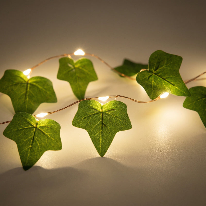 Decorative string lights with green leaf patterns on a neutral background