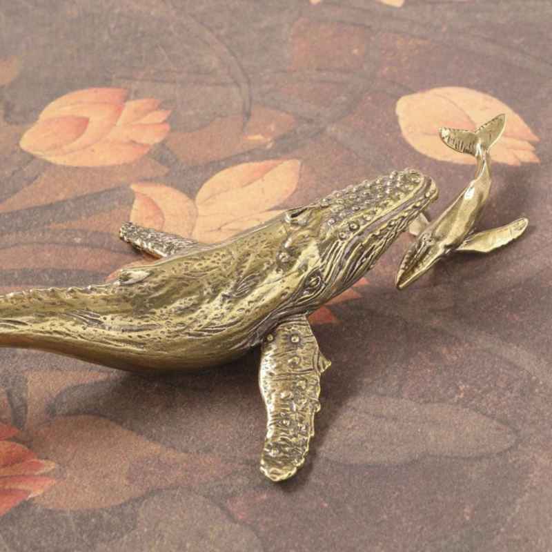 Bronze whale figurine on a decorative background with floral patterns