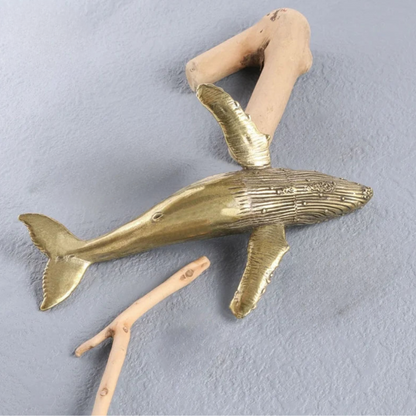 Brass whale wall decoration on a gray background