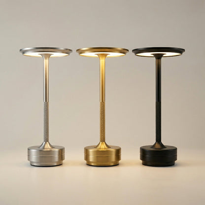 Three portable lamps in silver, gold, and black on a neutral background