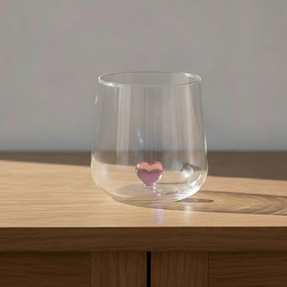 A clear glass with a pink heart at the bottom.